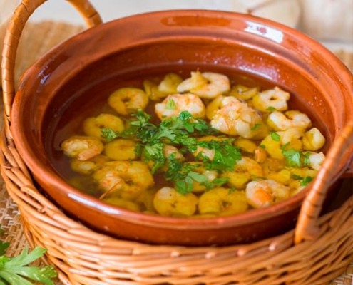 Gambas al ajillo servidas en cazuela de barro, con ajo dorado y aceite de oliva caliente