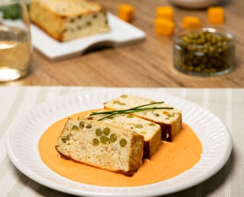 Pastel de calabaza y guisantes servido sobre salsa.