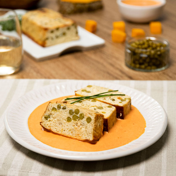 Pastel de calabaza y guisantes servido sobre salsa.