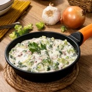 Brócoli con jamón en salsa cremosa, servido caliente en plato hondo
